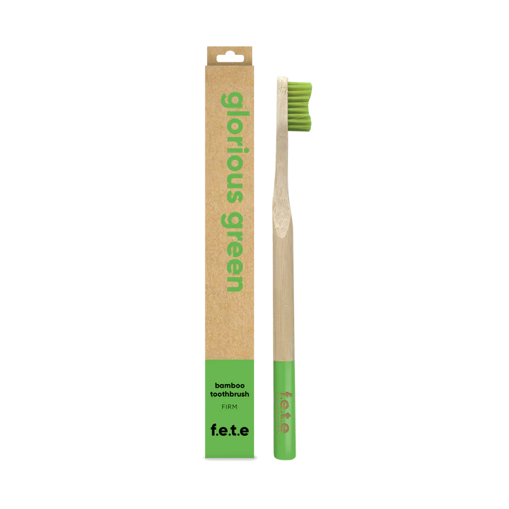 The F.E.T.E. Single Firm Bamboo Toothbrush has green bristles and tip, and is packaged in a brown and green box labeled "Glorious Green," available at Fisa Health.