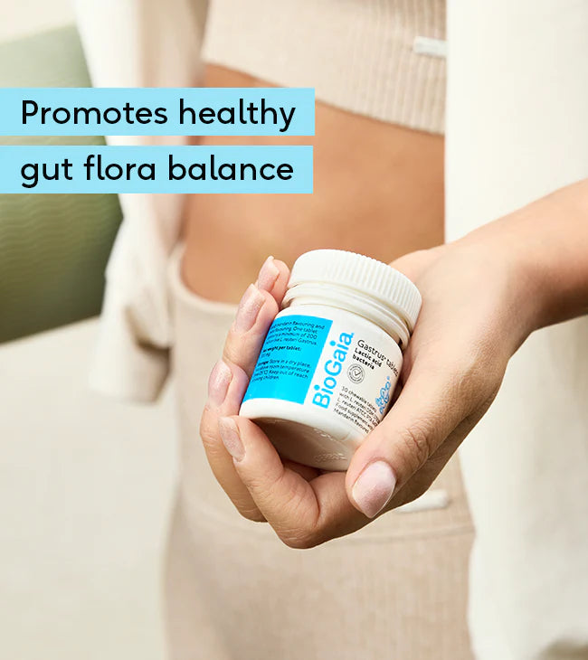 A person holds a BioGaia Gastrus Tablets 30s bottle near their waist. The packaging shows the BioGaia brand and product name. Available at Fisa Health.