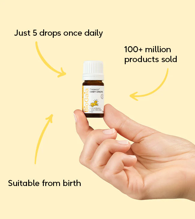 A hand holds a box labeled "BioGaia Protectis Baby Drops 5ml", showing a cartoon baby and product information. Available at Fisa Health.