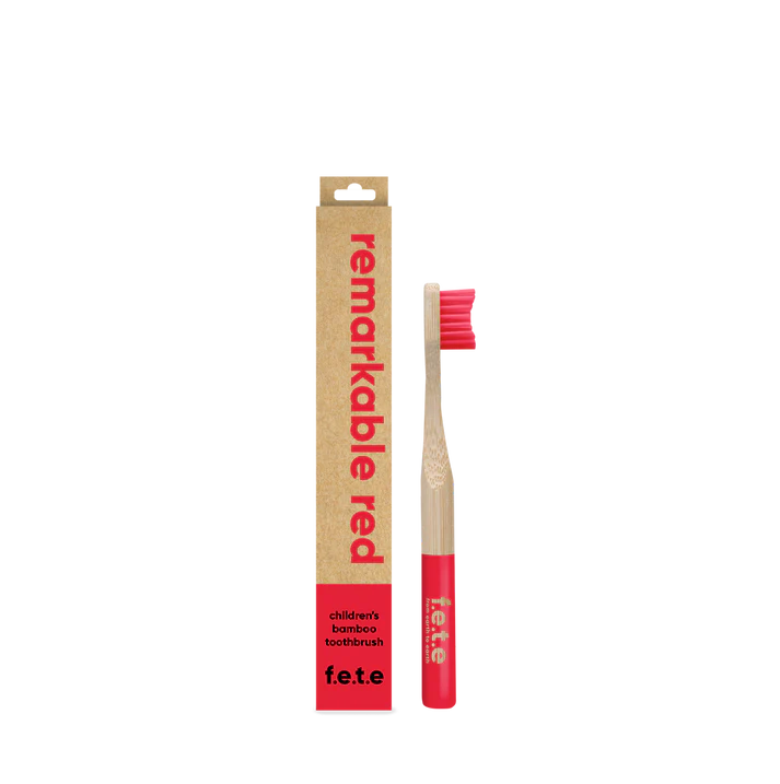 A F.E.T.E. Children's Bamboo Toothbrush with red bristles and handle is displayed next to its "remarkable red" cardboard box, available at Fisa Health.