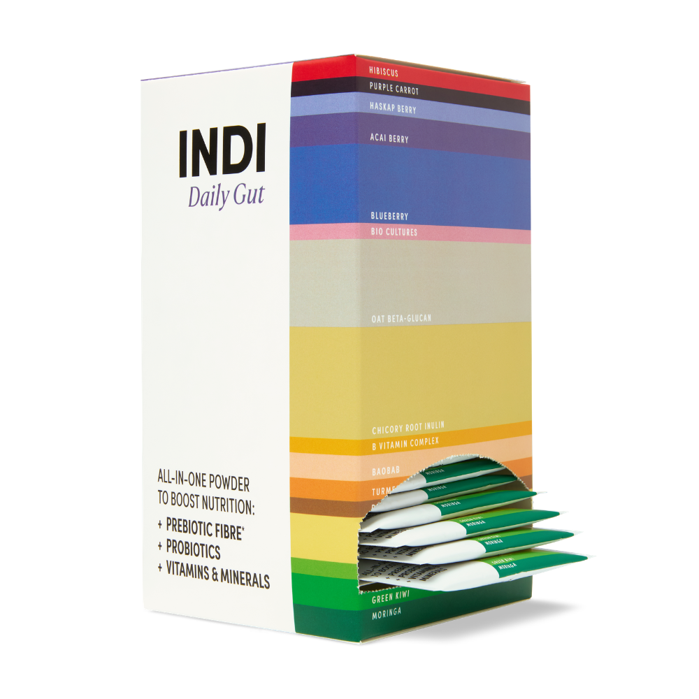 A box of INDI Daily Gut High Fibre Powder (28 x 12g) with colorful bands, featuring plant-based prebiotic fibre; green and white sachets partially pulled out. Available at Fisa Health.
