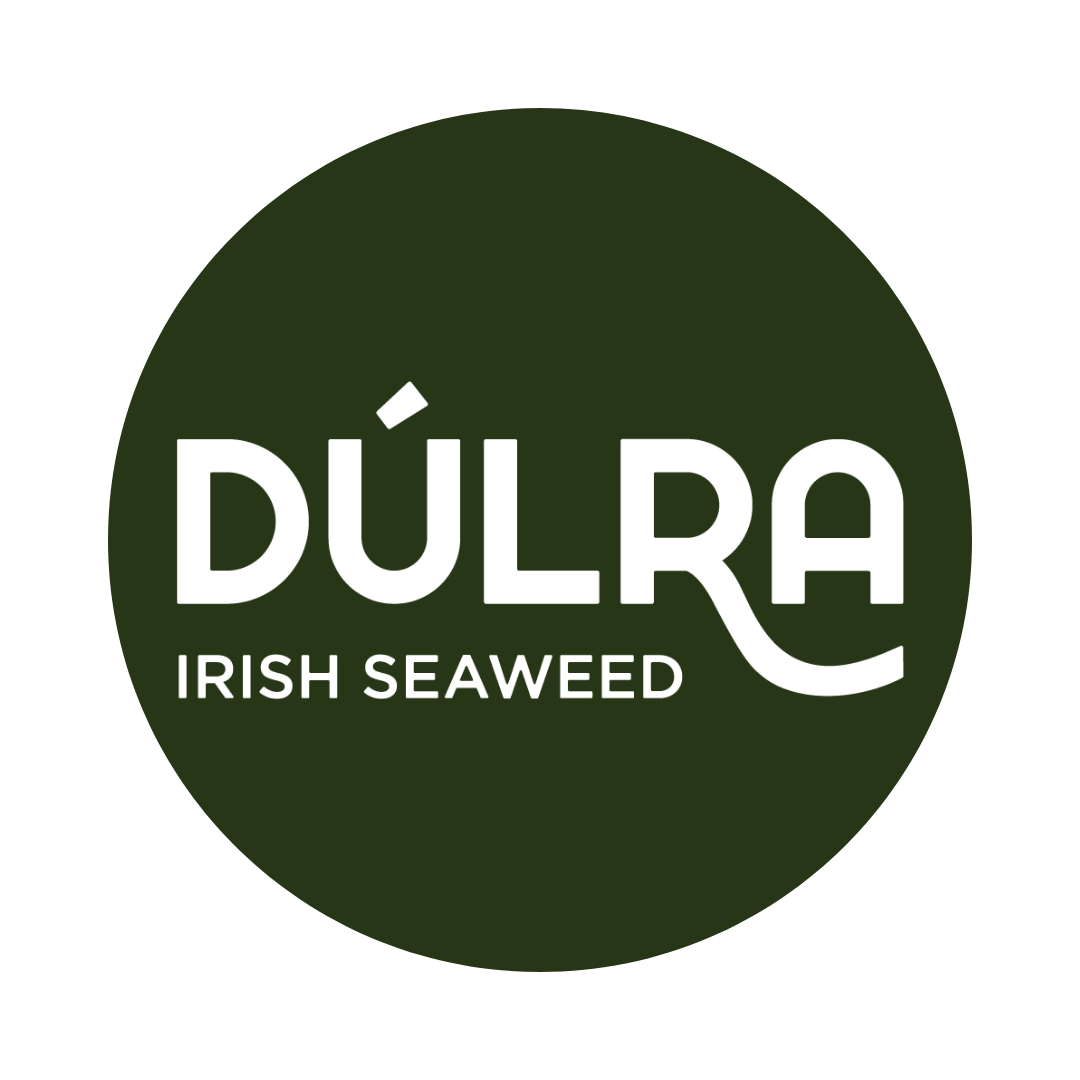 Logo with a dark green circle featuring the white text DÚLRA IRISH SEAWEED. The letter R in DÚLRA has an extended curved leg resembling seaweed.