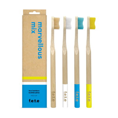 Four F.E.T.E. Multipack Medium Soft Bamboo Toothbrushes with colored bristles and handles are arranged beside their eco-friendly, biodegradable, plastic-free box of 4, available at Fisa Health.
