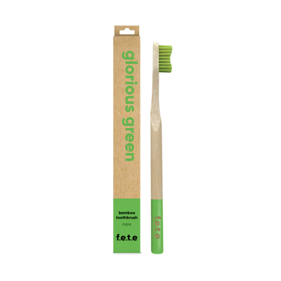 The F.E.T.E. Single Firm Bamboo Toothbrush has green bristles and tip, and is packaged in a brown and green box labeled "Glorious Green," available at Fisa Health.