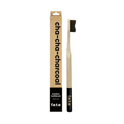The F.E.T.E. Single Medium Bamboo Toothbrush features black bristles, a biodegradable handle, and is packaged in a “cha-cha-charcoal” box, available at Fisa Health.