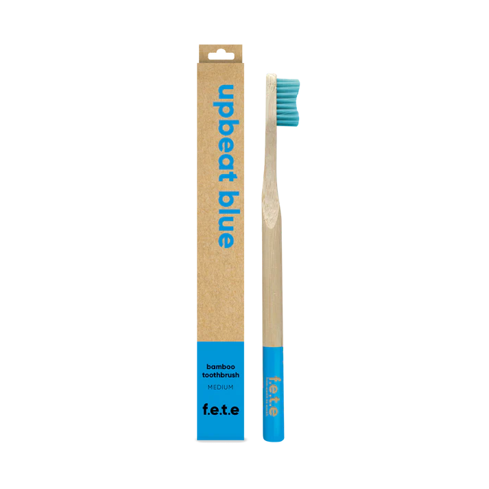 F.E.T.E. Single Medium Bamboo Toothbrush with a biodegradable handle, blue bristles and tip, packaged in an eco-friendly "upbeat blue" box, available at Fisa Health.