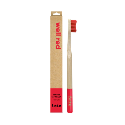 The F.E.T.E. Single Medium Bamboo Toothbrush features red bristles, a matching base, and a biodegradable handle, shown in a "well red" box labeled "bamboo toothbrush", available at Fisa Health.