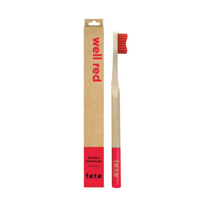 The F.E.T.E. Single Medium Bamboo Toothbrush features red bristles, a matching base, and a biodegradable handle, shown in a "well red" box labeled "bamboo toothbrush", available at Fisa Health.
