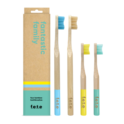 Four F.E.T.E. Family Pack bamboo toothbrushes (2 adult, 2 children) with blue and yellow handles are displayed next to the product box, available at Fisa Health.