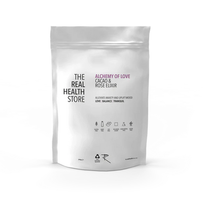 A white pouch labeled Alchemy Cacao & Rose Elixir - 330g, featuring Criollo cacao and rose petal powder, with product details and icons shown on the front, available at Fisa Health.