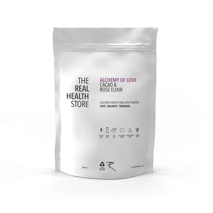 A white pouch labeled Alchemy Cacao & Rose Elixir - 330g, featuring Criollo cacao and rose petal powder, with product details and icons shown on the front, available at Fisa Health.