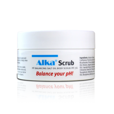 A white jar labeled Alka® Scrub features blue and black text, with “Balance your pH!” in red below the label. Available at Fisa Health.