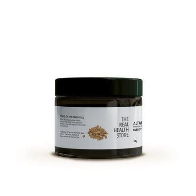 A dark jar with a white label and black lid displaying the text "Altai White Shilajit, Premium Brakshun Stone Oil 30g" with product details and several small brown pieces nearby, available at Fisa Health.