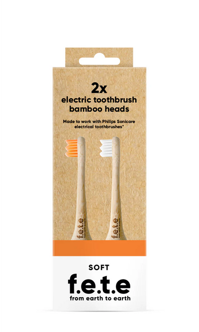 Two F.E.T.E Electric Compatible bamboo toothbrush heads, one with orange bristles and one with white bristles, in eco packaging labeled soft, available at Fisa Health.