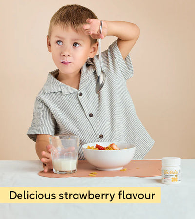 A young boy smiles at a table with cereal, strawberries, milk, and BioGaia Protectis Strawberry Kids Tablets 30s. Text: Delicious strawberry flavour, available at Fisa Health.