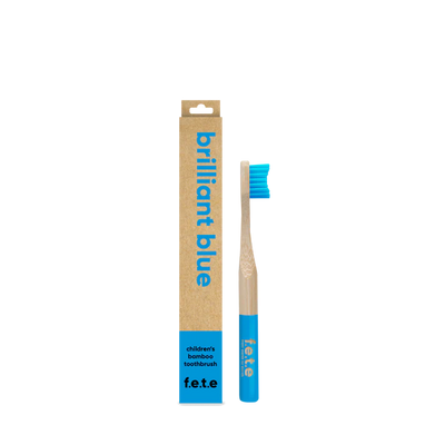 A F.E.T.E. Children's Bamboo Toothbrush with blue bristles and tip, next to its brown box labeled "Brilliant Blue", available at Fisa Health.