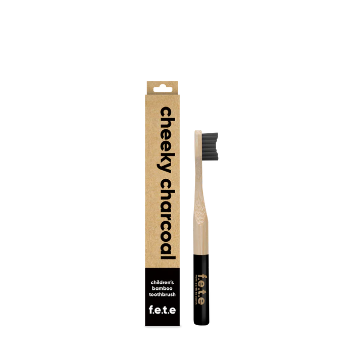 A F.E.T.E. Children's Bamboo Toothbrush with black bristles stands beside its brown "cheeky charcoal" box, with the brand name visible on the handle and packaging, available at Fisa Health.