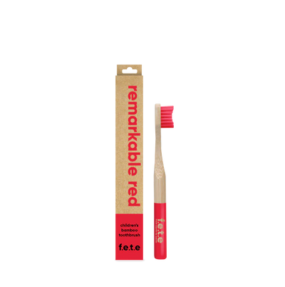A F.E.T.E. Children's Bamboo Toothbrush with red bristles and handle is displayed next to its "remarkable red" cardboard box, available at Fisa Health.