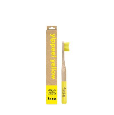 F.E.T.E. Children's Bamboo Toothbrush with yellow bristles and tip beside its box labeled “yippee! yellow” and “children’s bamboo toothbrush f.e.t.e.”, available at Fisa Health.