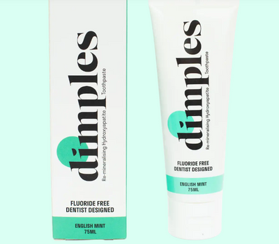 A tube and box of Dimples Hydroxyapatite Toothpaste, 75ml, Fluoride Free, English Mint flavor with white and green packaging, available at Fisa Health.