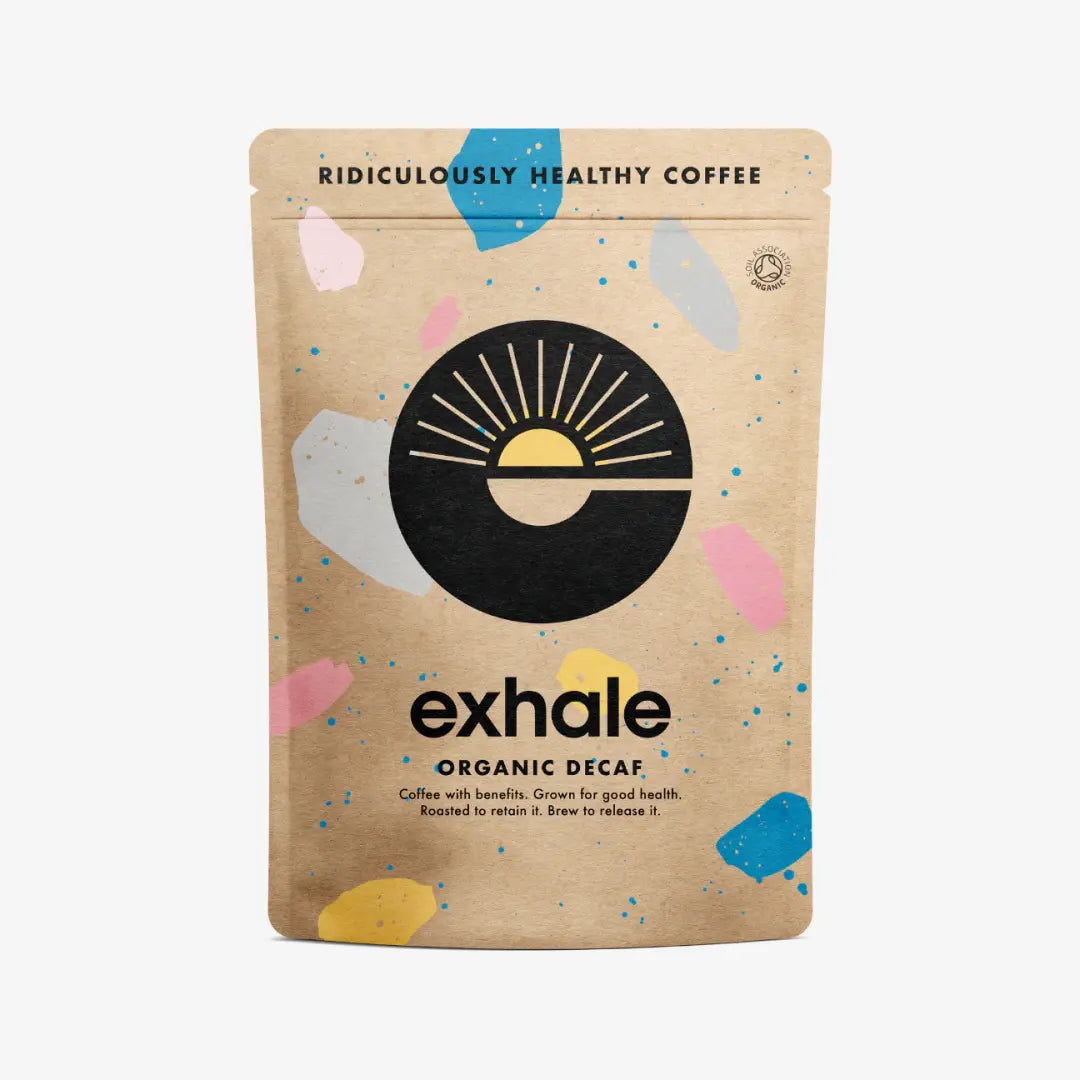 A brown bag labeled Exhale Coffee Decaf - Ground (Medium) displays a sun logo and colorful abstract shapes, with the phrase "Ridiculously Healthy Coffee." Available at Fisa Health.