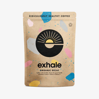 A brown bag labeled Exhale Coffee Decaf - Ground (Medium) displays a sun logo and colorful abstract shapes, with the phrase "Ridiculously Healthy Coffee." Available at Fisa Health.