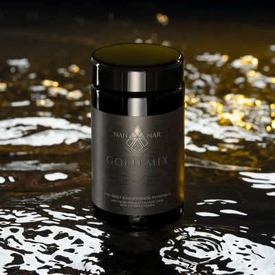 A black jar labeled Nannar Gold Mix rests on a gold-tinged surface with soft lighting, available at Fisa Health.