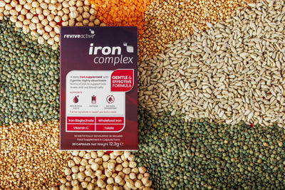 A box labeled "Revive Active Iron Complex" is displayed on a colorful background of mixed seeds and lentils, available at Fisa Health.
