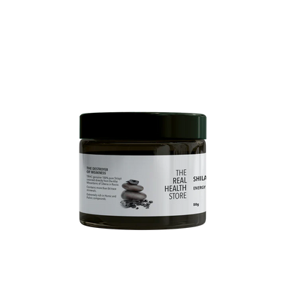 A dark jar labeled Premium Altai Shilajit Resin 50grams with a black lid, containing 50g of supplement paste, is pictured next to stacked stones and black resin, available at Fisa Health.