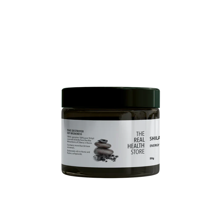 A dark jar labeled Premium Altai Shilajit Resin 50grams with a black lid, containing 50g of supplement paste, is pictured next to stacked stones and black resin, available at Fisa Health.
