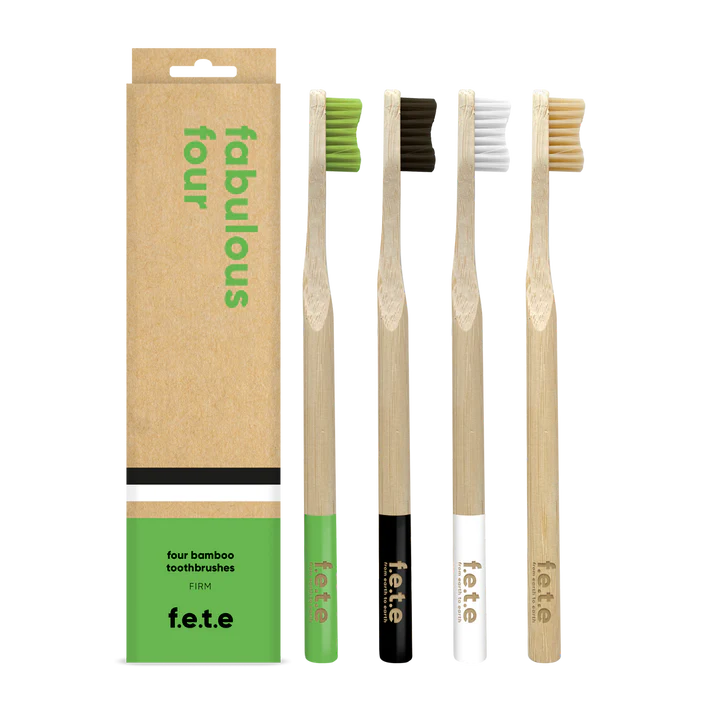 Four F.E.T.E. Multipack Firm Bamboo Toothbrushes in green, black, white, and natural are displayed next to a box labeled "fabulous four" and "four bamboo toothbrushes," available at Fisa Health.